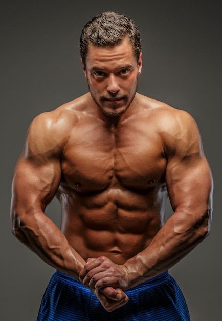 Bodybuilder showing his muscles. Isolated on grey