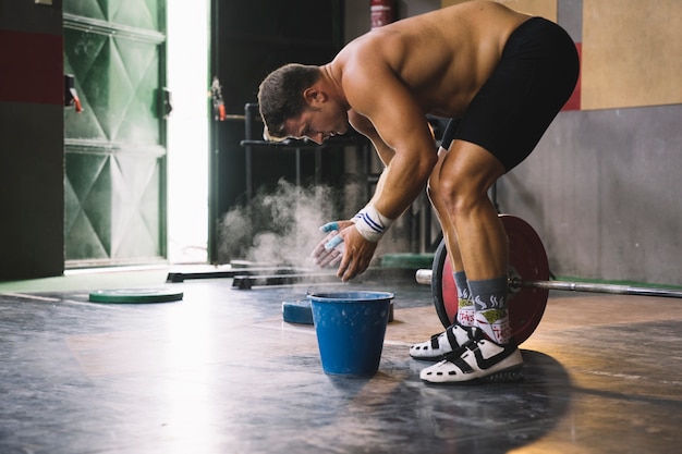 Concetto di bodybuilding con l'uomo che asciugano le mani con il magnesio