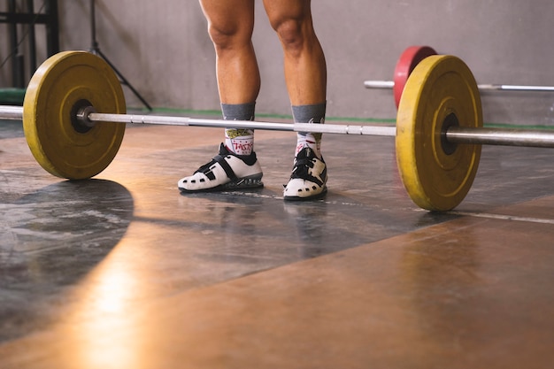 Foto gratuita concetto di bodybuilding con l'uomo in piedi davanti al barbell