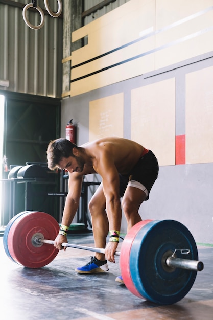 Bodybuilding concept with man touching barbell