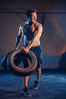 보디 빌딩 훈련, 근육질 몸매가 체육관에서 무거운 바퀴를 들어 올리는 수염 난 강한 운동가.