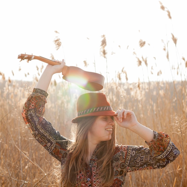 Free photo bohemian woman posing in the sun with ukulele