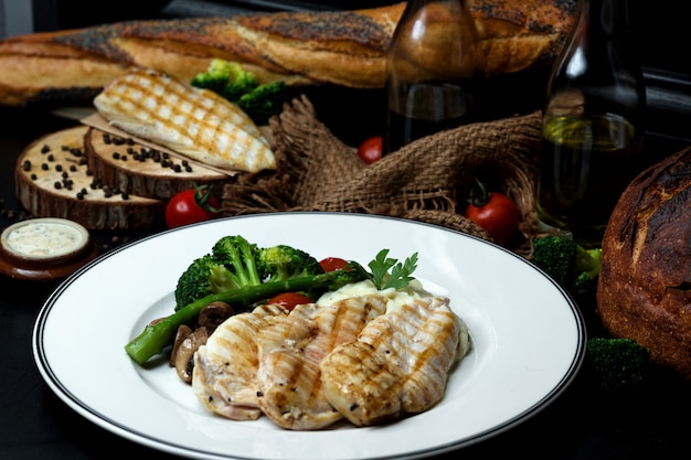 Boiled chicken breast served with broccoli, mushroom and tomato