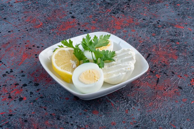Вареное яйцо в белой тарелке с сыром и зеленью.