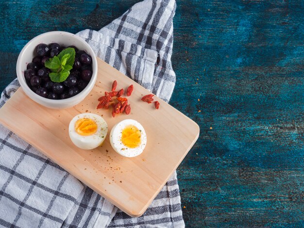 Boiled egg with berries on wooden board