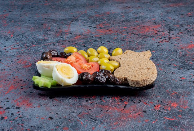 Boiled egg with black and green marinated olives and tomatoes. 