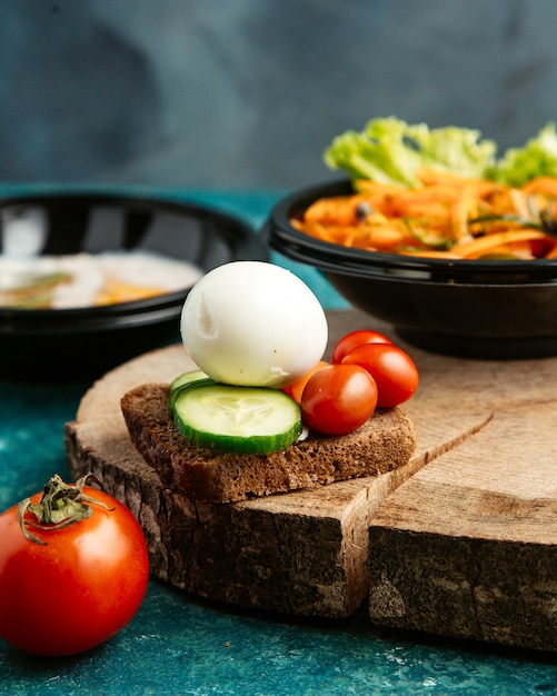 boiled egg with cucumber tomato and a slice of brown bread