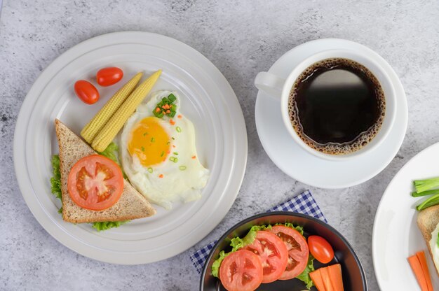 木のスプーンとコーヒーカップにトマトと鍋にゆで卵、ニンジン、トマト。