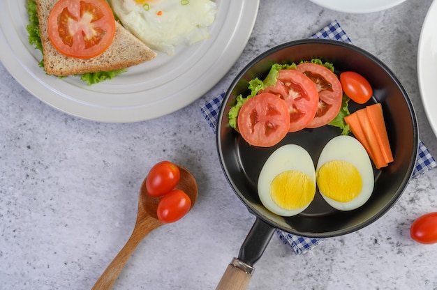 ゆで卵、にんじん、トマト、フライパンにトマト、木のスプーン。