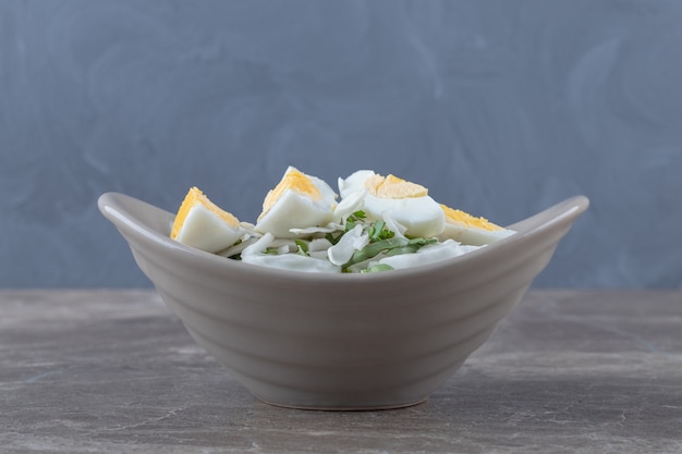 Boiled eggs and fresh salad in ceramic bowl.