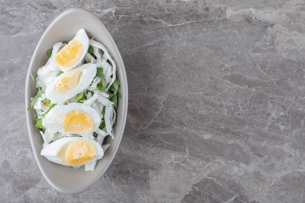 Uova sode e insalata fresca in ciotola di ceramica.