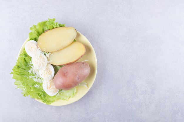 Boiled eggs and potatoes on yellow plate.