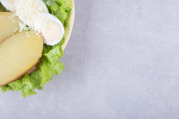 Boiled eggs and potatoes on yellow plate. 