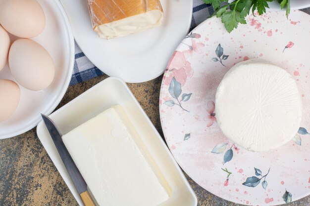 Boiled eggs and various cheese on plates.