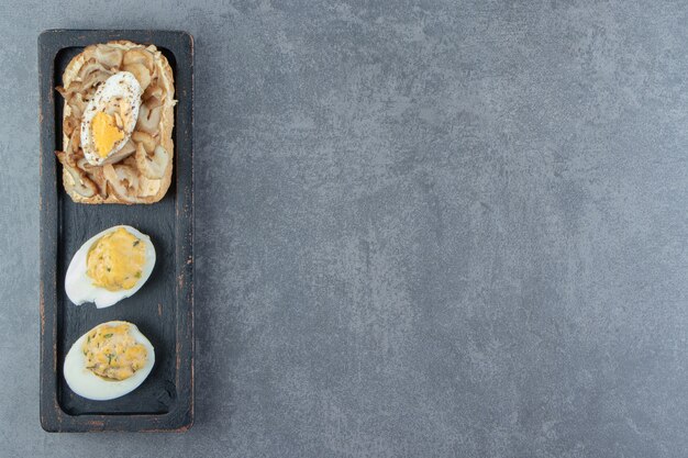 Free photo boiled eggs with bread on black plate.