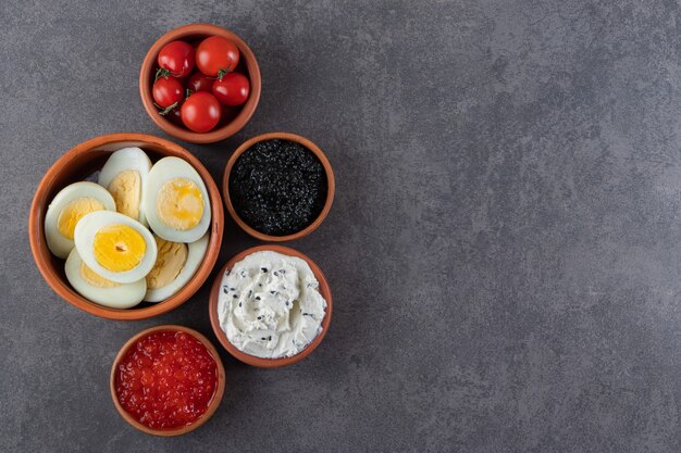 Boiled eggs with red and black caviar placed on a stone background .