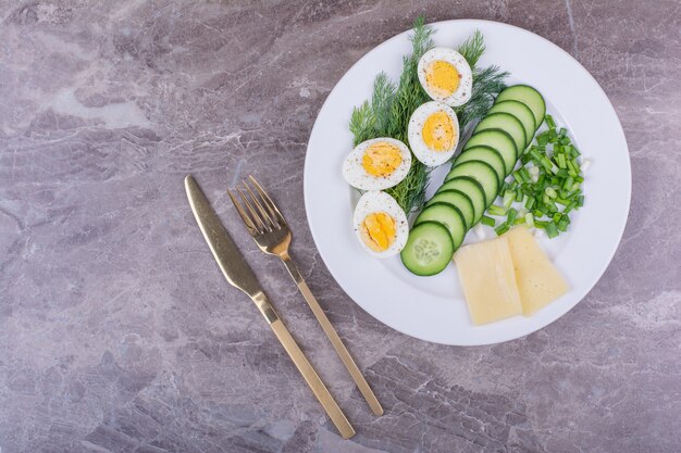 Boiled eggs with sliced cucumber and herbs