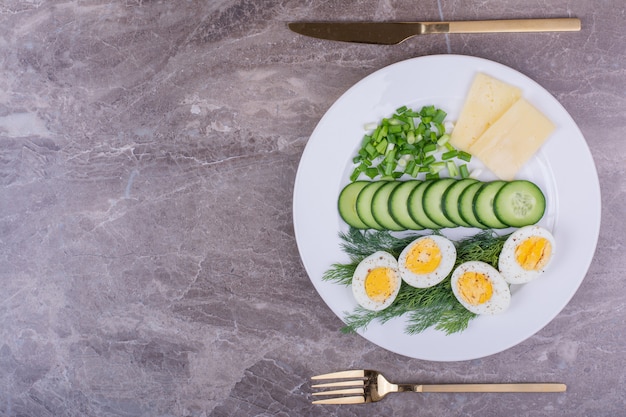 Free photo boiled eggs with sliced cucumber and herbs