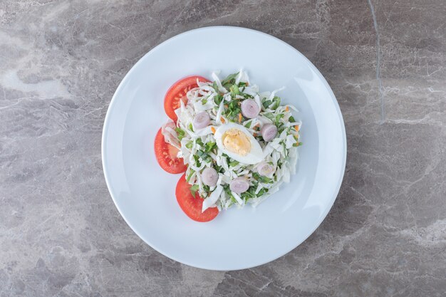 Boiled eggs with vegetable salad on white plate.