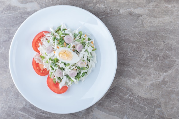 Boiled eggs with vegetable salad on white plate. 