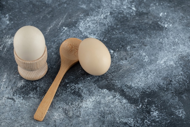 Boiled eggs and wooden spoon on marble.