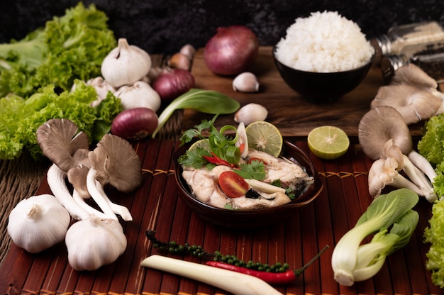 Boiled fish infusion with tomatoes, mushrooms, coriander, spring onion and lemongrass in a bowl