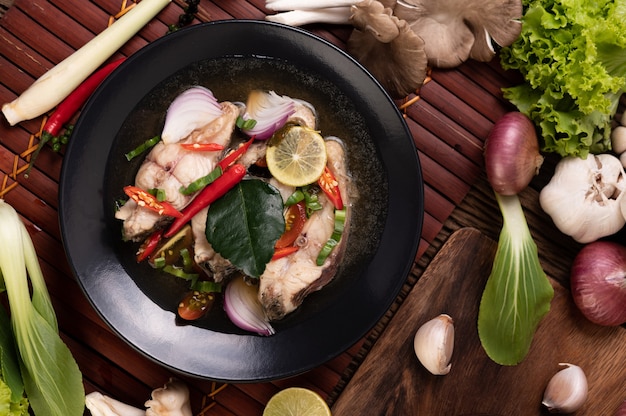 Boiled fish infusion with tomatoes, mushrooms, coriander, spring onion and lemongrass in a bowl