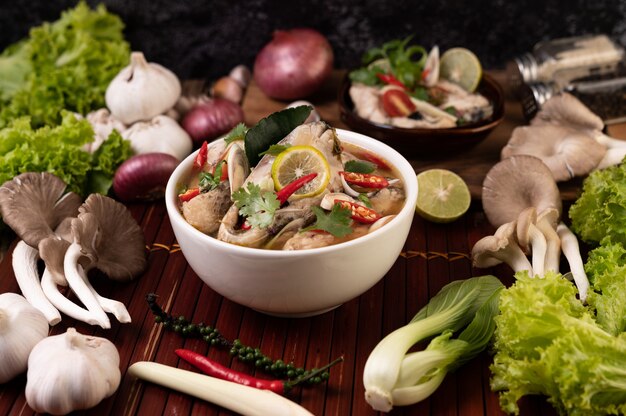 Boiled fish infusion with tomatoes, mushrooms, coriander, spring onion and lemongrass in a bowl