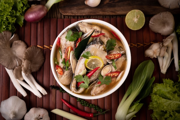 Free photo boiled fish infusion with tomatoes, mushrooms, coriander, spring onion and lemongrass in a bowl