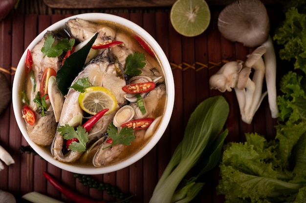 Boiled fish infusion with tomatoes, mushrooms, coriander, spring onion and lemongrass in a bowl