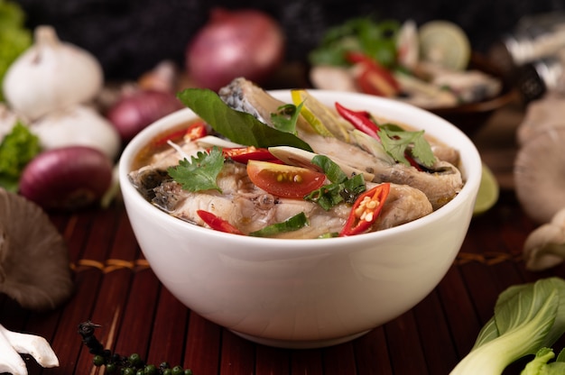 Boiled fish infusion with tomatoes, mushrooms, coriander, spring onion and lemongrass in a bowl