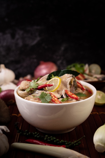 Boiled fish infusion with tomatoes, mushrooms, coriander, spring onion and lemongrass in a bowl