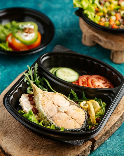  boiled fish with vegetables and herbs on a blackboard