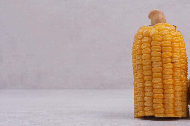 Boiled half cut corn on white table.