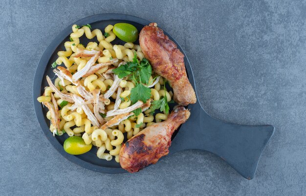 Boiled pasta and chicken legs on black board. 