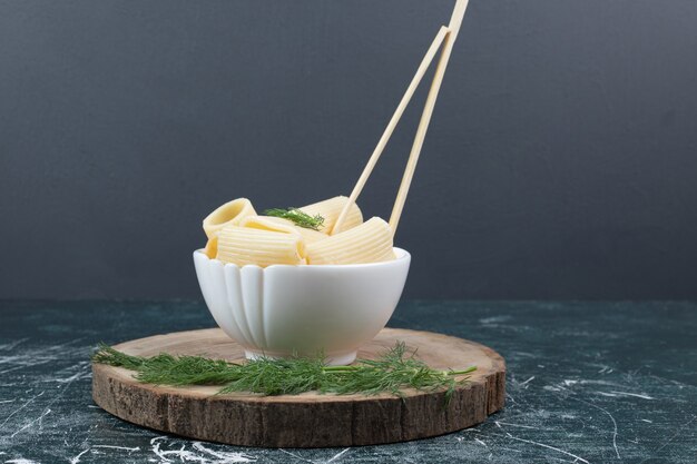 Free photo boiled pasta in white bowl with chopsticks and coriander. high quality photo