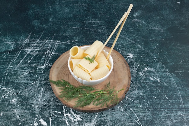 Boiled pasta in white bowl with chopsticks and coriander.