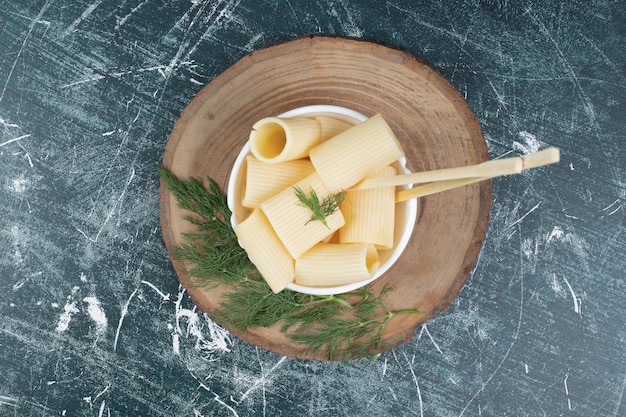 Free photo boiled pasta in white bowl with chopsticks and coriander.