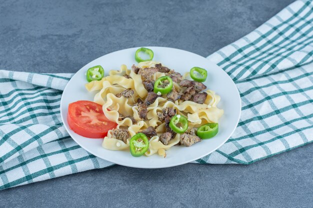 Boiled pasta with meat pieces on white plate.