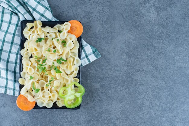 黒いプレートに野菜と煮たパスタ。