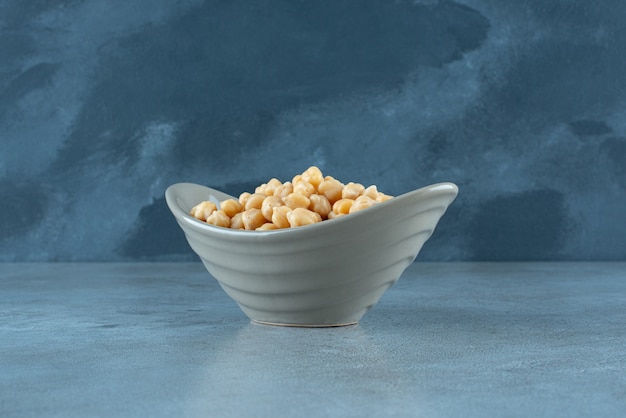 Boiled pea beans in a cup on blue background. High quality photo