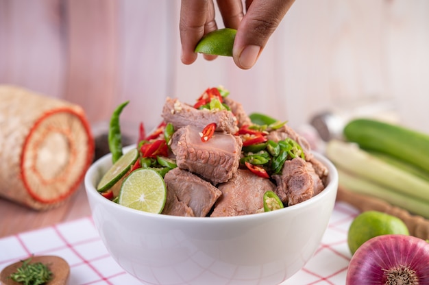 Boiled pork ribs in a white cup on a piece of fabric on a wooden table.