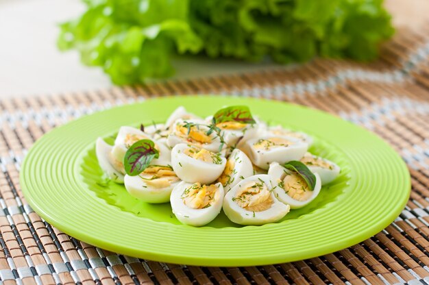 Boiled quail eggs halves on a green plate