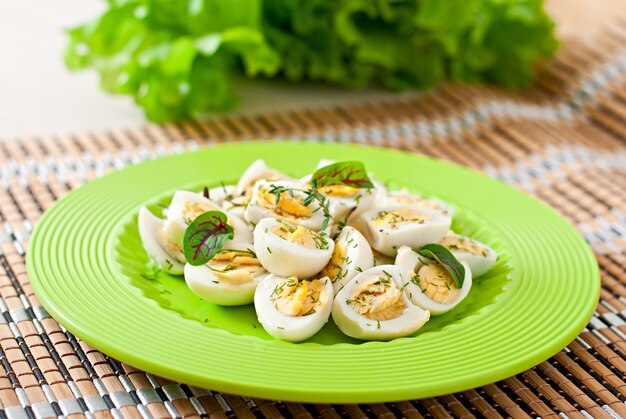 Boiled quail eggs halves on a green plate