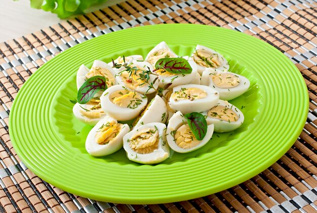 Boiled quail eggs halves on a green plate