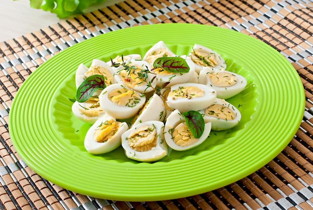 Вареные яйца перепелиные половинки на зеленой тарелке