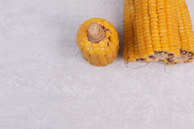 Boiled ripe corns on white table.