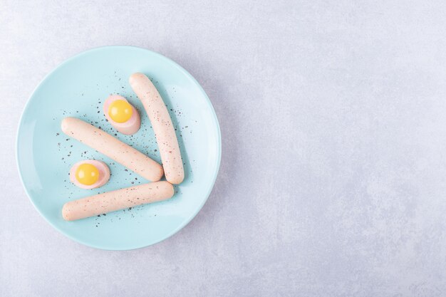 Boiled sausages and egg yolk on blue plate. 