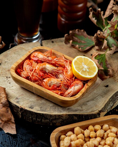 Boiled shrimps served with lemon half in bamboo serving