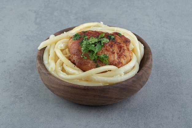 Foto gratuita spaghetti bolliti e pollo arrosto in ciotola di legno.